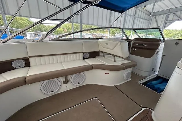 Slide: The Image of Interior of a 2011 Cobalt 302 boat with beige seating and blue canopy. - 9