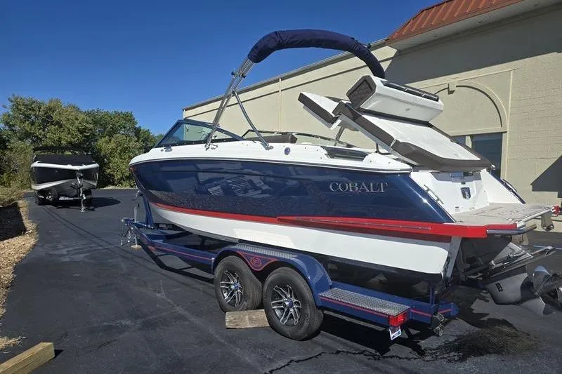 The Image of 2022 Cobalt R4 boat on trailer, blue and white design, parked outdoors. - 2
