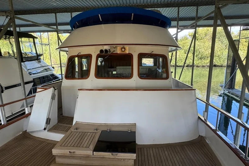 Slide: The Image of 1979 De Fever Pilot House boat docked under a covered marina, showcasing its classic design. - 14