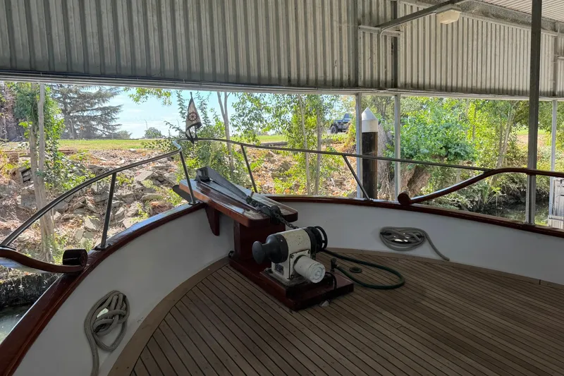 Slide: The Image of 1979 De Fever Pilot House boat docked under a metal canopy, surrounded by trees. - 15