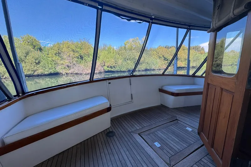 Slide: The Image of 1979 De Fever Pilot House interior with wooden flooring and cushioned seating, overlooking lush greenery. - 17
