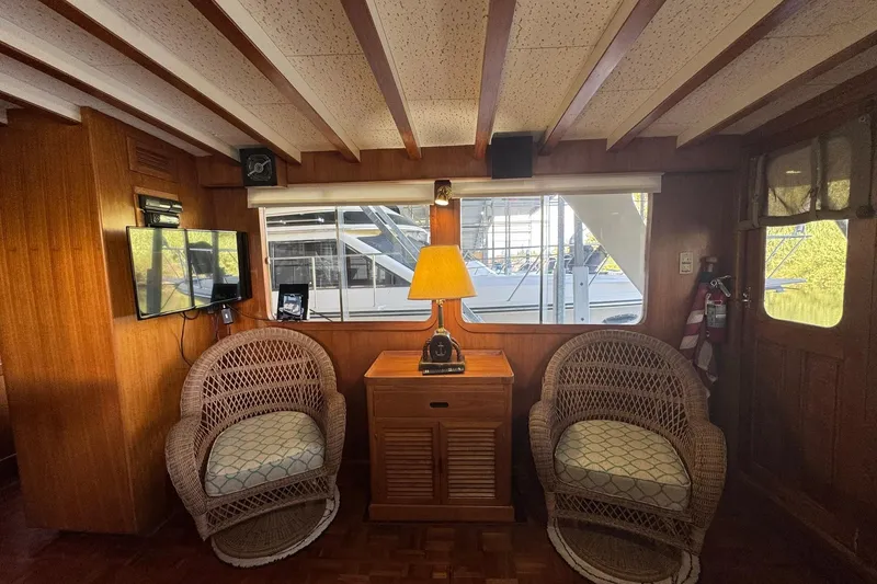 Slide: The Image of 1979 De Fever Pilot House interior with wicker chairs, lamp, and window view of marina. - 23