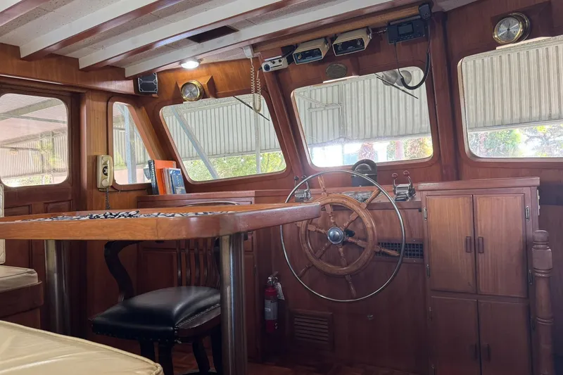 Slide: The Image of 1979 De Fever Pilot House interior with wooden helm, table, and nautical decor. - 35