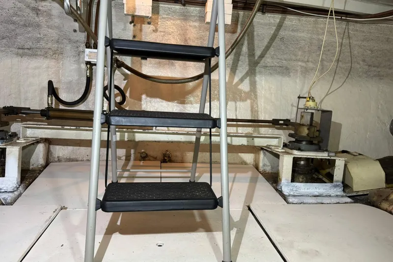 Slide: The Image of Engine room of 1979 De Fever Pilot House with ladder and mechanical components. - 56