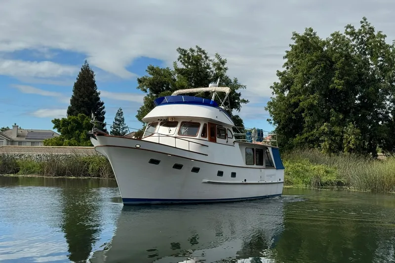 Slide: The Image of 1979 De Fever Pilot House boat cruising on a calm river, surrounded by lush greenery. - 7