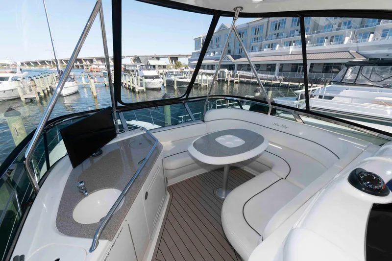 Slide: The Image of 2006 Sea Ray 52 Sedan Bridge yacht interior with seating and table, docked at marina. - 12