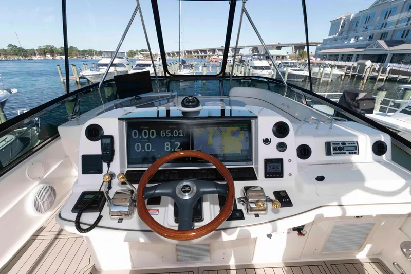 Slide: The Image of 2006 Sea Ray 52 Sedan Bridge helm with navigation equipment and wooden steering wheel. - 13