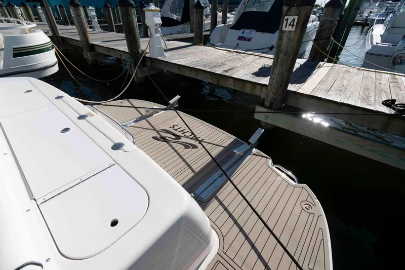 Slide: The Image of 2006 Sea Ray 52 Sedan Bridge yacht docked at marina, showing swim platform and mooring lines. - 20