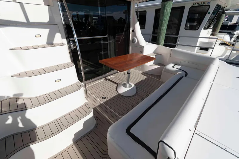 Slide: The Image of 2006 Sea Ray 52 Sedan Bridge yacht deck with seating and wooden table. - 4