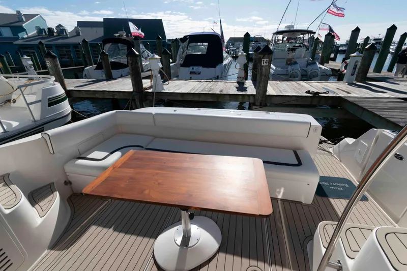 Slide: The Image of 2006 Sea Ray 52 Sedan Bridge yacht with outdoor seating and wooden table at marina. - 6