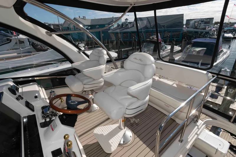 Slide: The Image of 2006 Sea Ray 52 Sedan Bridge helm with luxurious white seating and wooden steering wheel. - 7