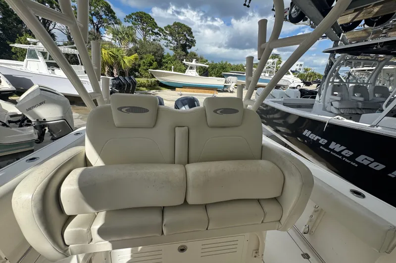 Slide: The Image of 2014 Cobia 296 Center Console boat interior with cushioned seating and multiple boats in the background. - 17