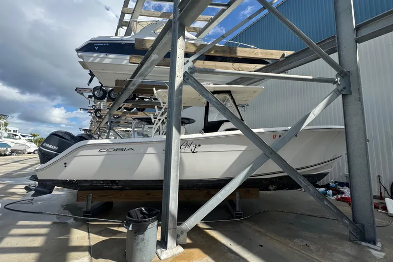 Slide: The Image of 2014 Cobia 296 Center Console boat stored on a rack, featuring Yamaha engines. - 4
