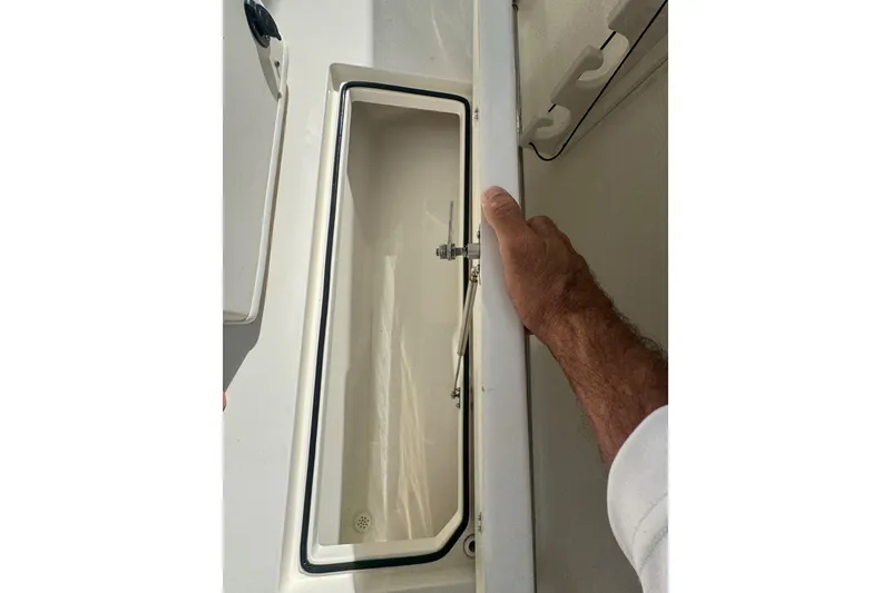 Slide: The Image of 2014 Cobia 296 Center Console storage compartment with open lid and hand holding it. - 8