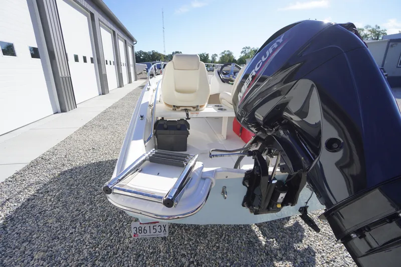 Slide: The Image of 2023 Boston Whaler 130 Super Sport boat with Mercury engine, parked on gravel near a building. - 19