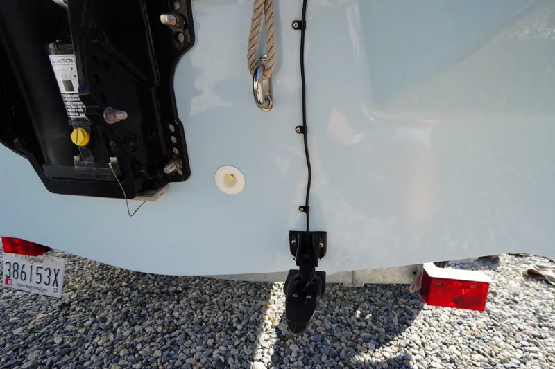 Slide: The Image of Rear view of 2023 Boston Whaler 130 Super Sport boat on gravel, showing motor and license plate. - 20