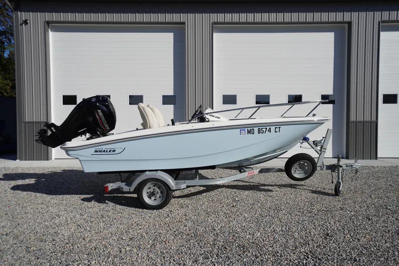 Slide: The Image of 2023 Boston Whaler 130 Super Sport boat on trailer, parked outside a garage. - 21