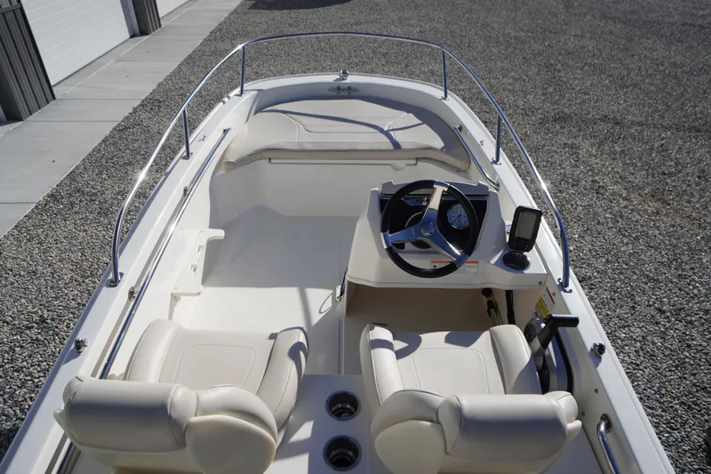 Slide: The Image of 2023 Boston Whaler 130 Super Sport boat interior with steering wheel and seating. - 23