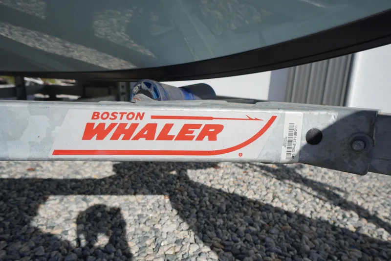 Slide: The Image of Boston Whaler 130 Super Sport 2023 boat trailer with logo on gravel surface. - 41