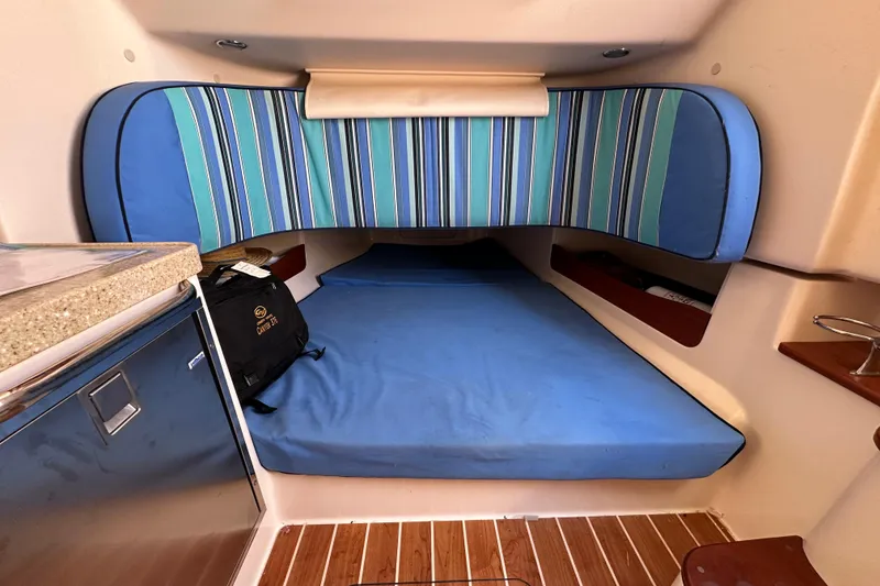 Slide: The Image of 2014 Grady-White Canyon 376 cabin interior with blue striped cushions and wooden flooring. - 25