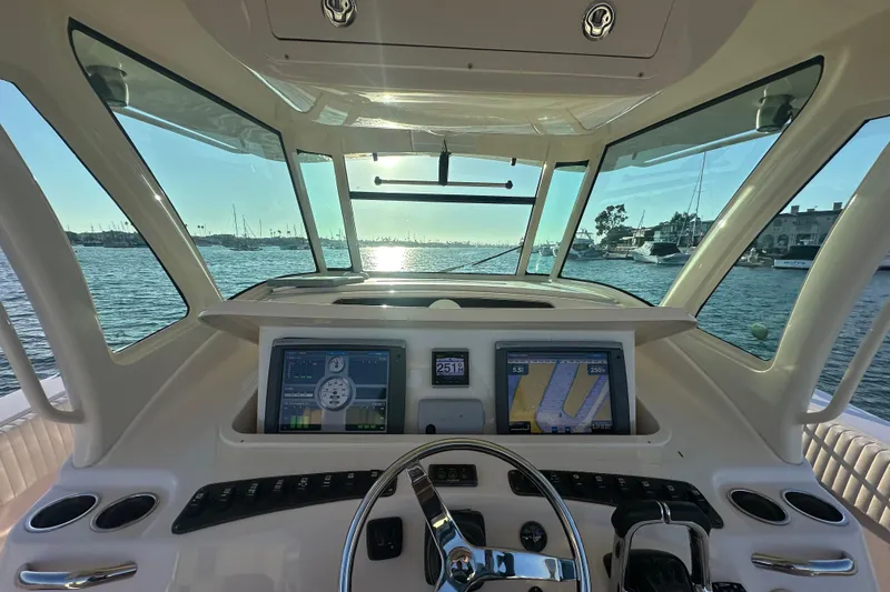 Slide: The Image of 2014 Grady-White Canyon 376 helm with navigation screens, steering wheel, and ocean view. - 6