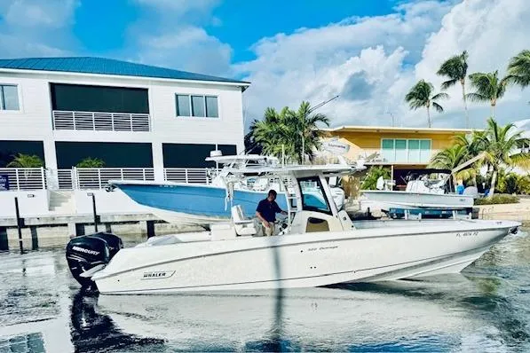 Slide: The Image of 2016 Boston Whaler 320 Outrage boat docked near waterfront homes with palm trees. - 17
