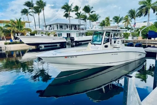 Slide: The Image of 2016 Boston Whaler 320 Outrage boat docked, surrounded by palm trees and waterfront homes. - 20