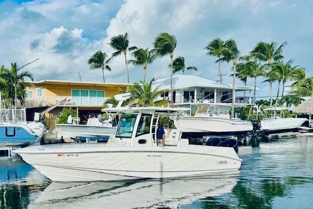 Slide: The Image of 2016 Boston Whaler 320 Outrage boat docked near tropical waterfront homes. - 21