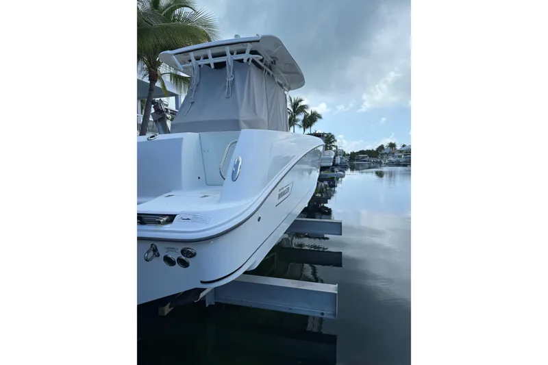 Slide: The Image of 2016 Boston Whaler 320 Outrage boat docked by palm trees and calm water. - 4