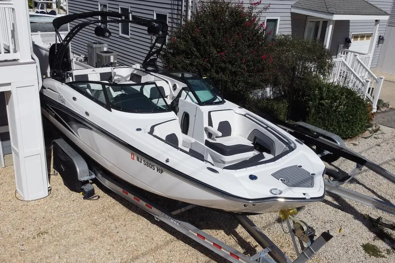 Slide: The Image of 2021 Monterey M-65 boat on trailer, parked beside a house, ready for transport. - 2