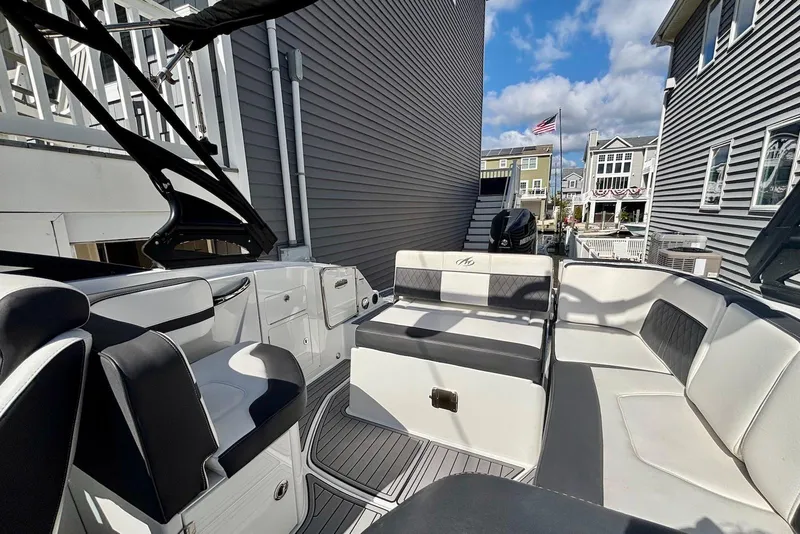 Slide: The Image of 2021 Monterey M-65 boat interior with seating, docked between houses under a blue sky. - 8