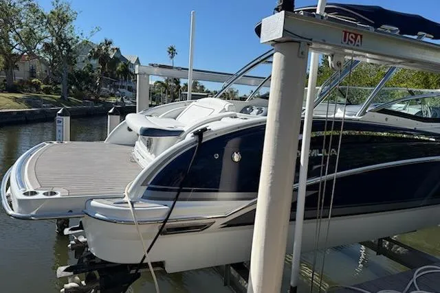 Slide: The Image of 2015 Formula 310 Bowrider boat docked on a lift in a scenic canal. - 2