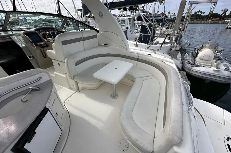 Slide: The Image of 2003 Sea Ray 320 Sundancer cockpit with white seating and table, docked at marina. - 12