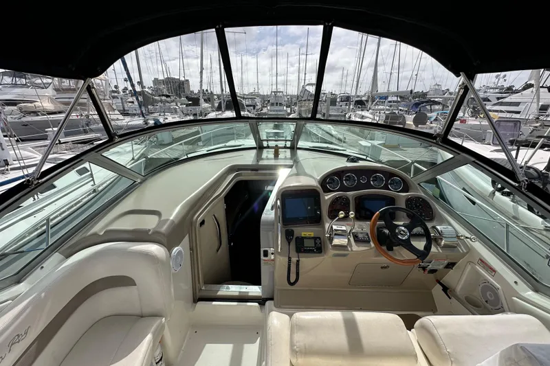 Slide: The Image of 2003 Sea Ray 320 Sundancer cockpit with steering wheel, controls, and marina view. - 16
