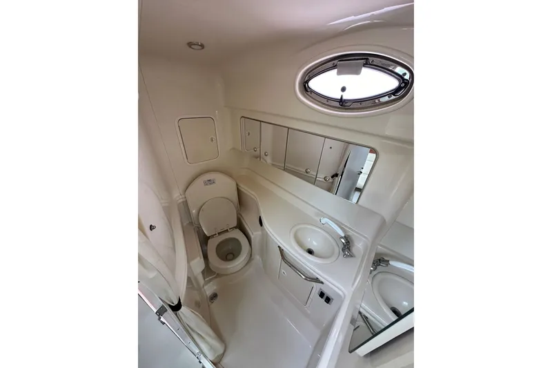 Slide: The Image of Bathroom interior of 2003 Sea Ray 320 Sundancer yacht, featuring toilet, sink, and porthole window. - 31