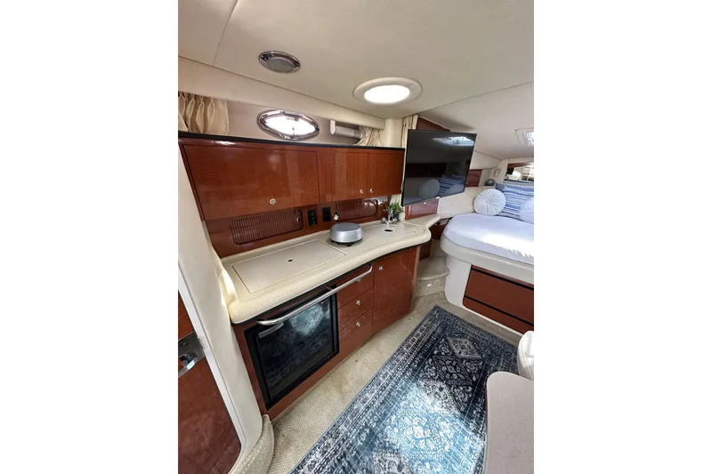 Slide: The Image of Interior of 2003 Sea Ray 320 Sundancer yacht with kitchenette and cozy sleeping area. - 32