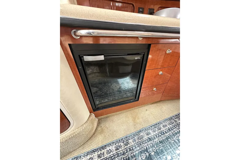 Slide: The Image of Interior of 2003 Sea Ray 320 Sundancer with built-in mini fridge and wooden cabinetry. - 33