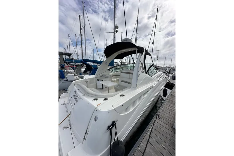 Slide: The Image of 2003 Sea Ray 320 Sundancer docked at marina, showcasing sleek design and spacious deck. - 7