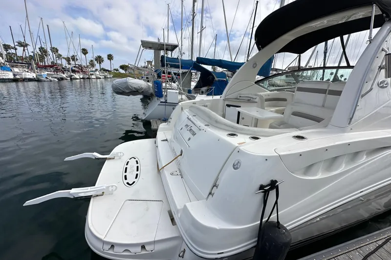 Slide: The Image of 2003 Sea Ray 320 Sundancer docked at marina, showcasing sleek design and spacious deck. - 8