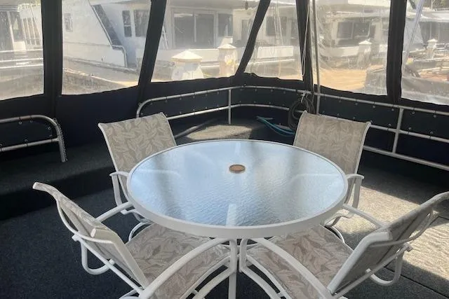 Slide: The Image of 1985 Jamestowner 16 x 63 houseboat interior with round glass table and chairs. - 2