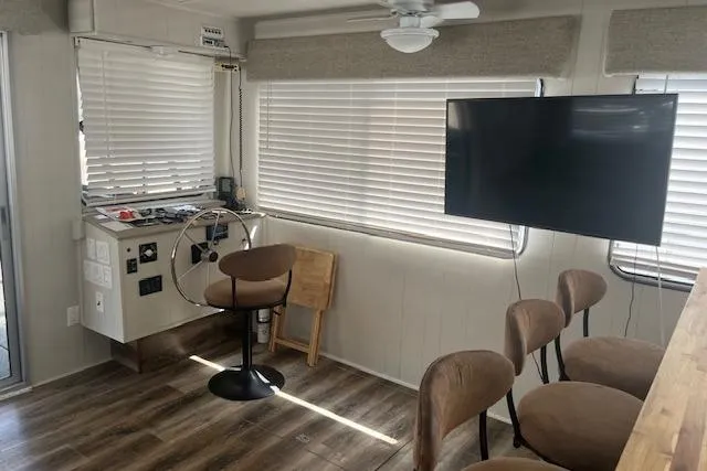 Slide: The Image of 1985 Jamestowner 16 x 63 houseboat interior with helm, seating, and mounted TV. - 4