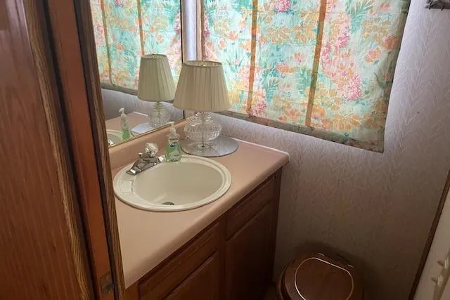 Slide: The Image of 1992 Jamestowner houseboat bathroom with sink, floral curtains, and wooden cabinetry. - 10