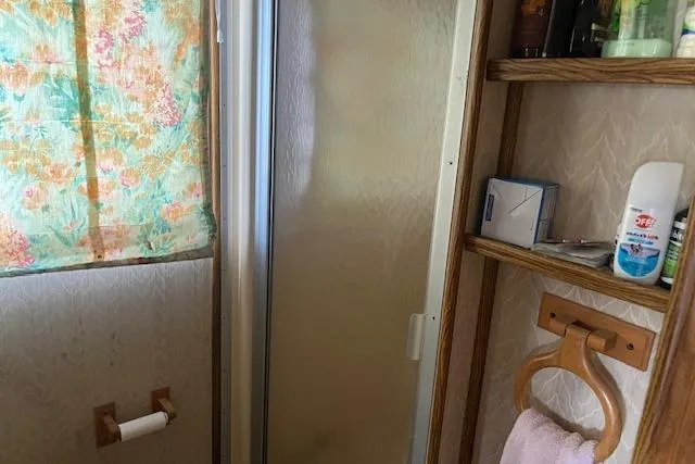 Slide: The Image of Bathroom interior of a 1992 Jamestowner 16x72 houseboat with shower and wooden shelves. - 16