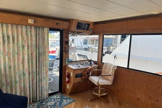 Slide: The Image of Interior of a 1992 Jamestowner 16x72 houseboat with helm, chair, and floral curtains. - 2