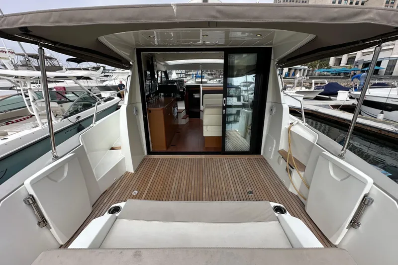 Slide: The Image of 2015 Jeanneau NC11 yacht with open deck and sliding glass doors at marina. - 10