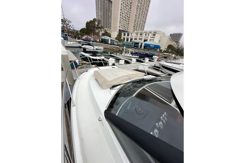 Slide: The Image of 2015 Jeanneau NC11 yacht docked in a marina with cityscape background. - 17