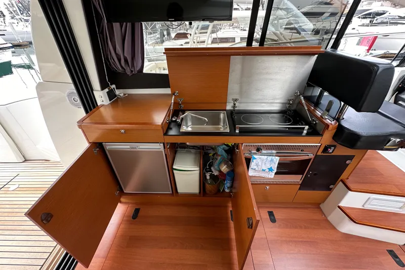 Slide: The Image of 2015 Jeanneau NC11 yacht kitchen with stove, sink, fridge, and storage cabinets. - 33