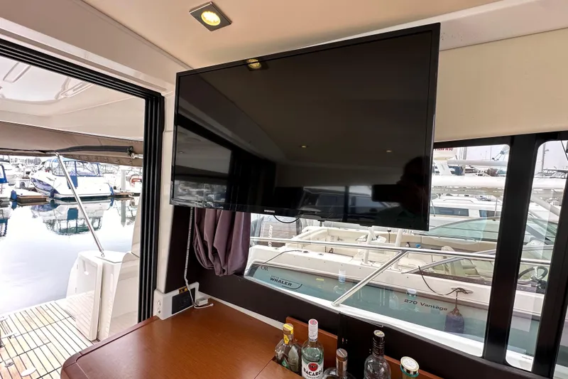 Slide: The Image of Interior of 2015 Jeanneau NC11 yacht with TV and bar setup, overlooking marina. - 34
