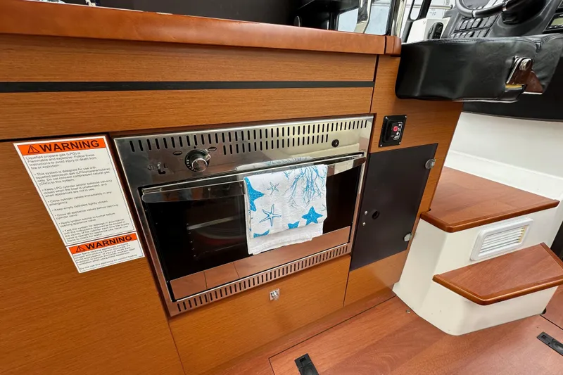 Slide: The Image of 2015 Jeanneau NC11 interior with wooden cabinetry and built-in oven. - 35