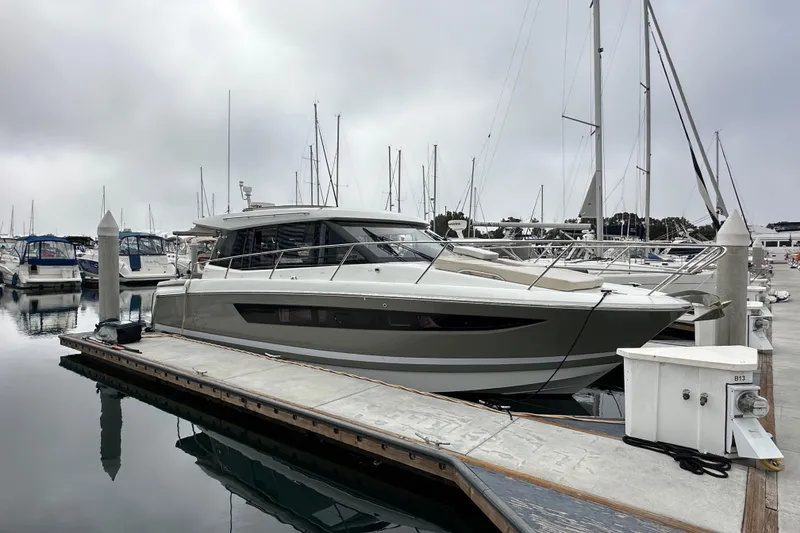 Slide: The Image of 2015 Jeanneau NC11 yacht docked at marina, surrounded by other boats. - 4